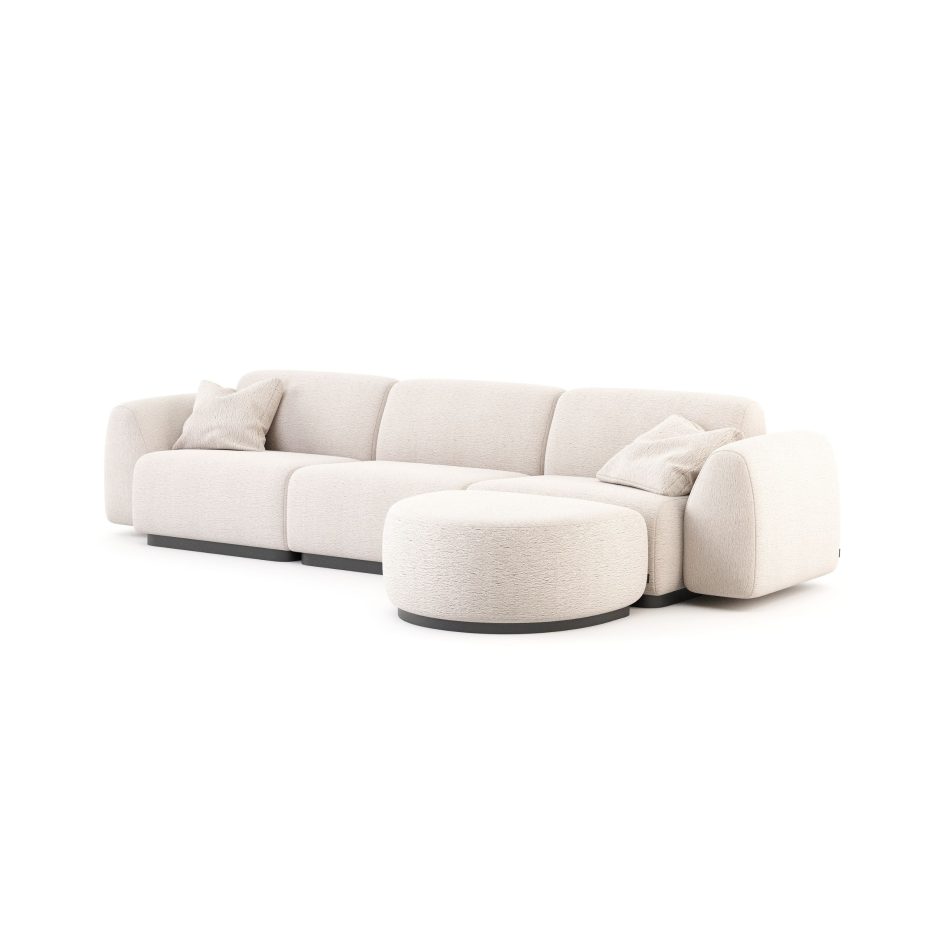 The Stone Sofa appears in a clean modular arrangement with a rounded ottoman, upholstered in soft beige fabric with plush, sculptural cushions and matching pillows, its low‑profile silhouette creating a serene focal point within a minimalist setting subtly shaped by curated modern furniture, gentle layers of living room inspiration, refined touches of contemporary furniture, and the warm, inviting comfort associated with bespoke furniture solutions.