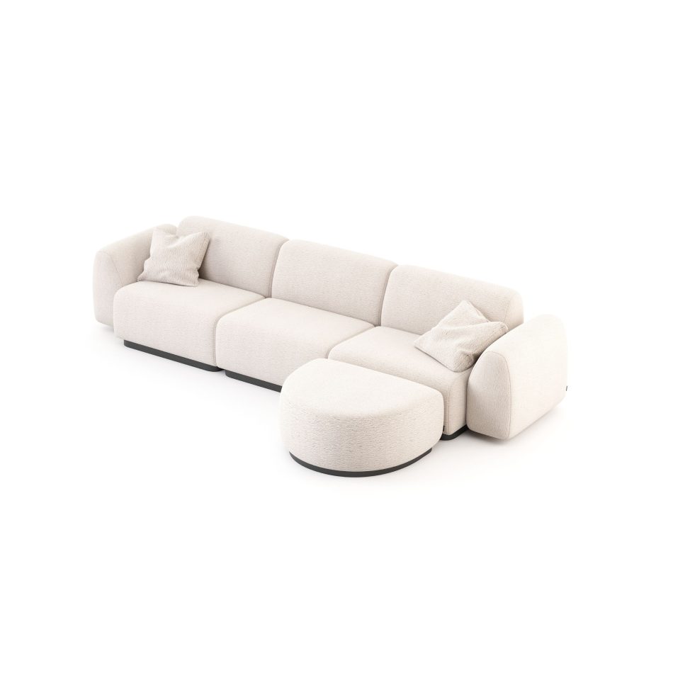 The Stone Sofa appears in a modular configuration with a rounded ottoman extension, upholstered in soft beige fabric with plush, sculptural cushions and matching pillows, its low‑profile silhouette creating a serene focal point within a contemporary setting subtly shaped by curated living room furniture, gentle layers of modern table design, refined touches of luxury home furniture, and the warm visual harmony associated with thoughtful interior design inspiration.