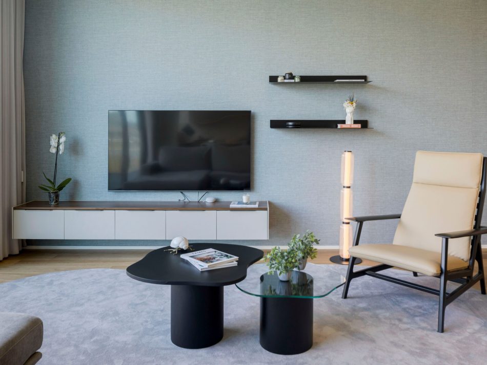 A serene modern living room anchored by the Landform TV cabinet, whose clean geometry defines the layout. The Ripa Armchair in dark oak and leather upholstery adds depth beside the sculptural lamp, while the Natur Side Tables introduce a light visual presence. The space reflects refined living room inspiration, elevated by luxury living room furniture, high end leather furniture, and warm wood texture.