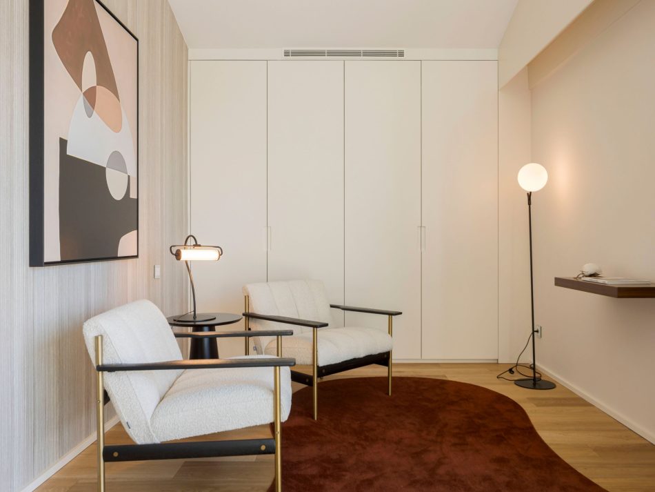 A quiet reading nook with two upholstered armchairs, the Olivier Side Table, and a sculptural floor lamp set against abstract artwork. The soft tones and natural materials create a composed environment enriched by home office furniture, refined bedroom furniture‑style comfort, warm wood texture, and elegant bespoke furniture touches.