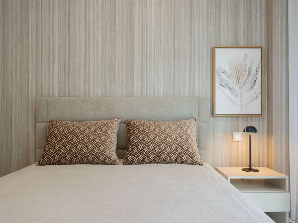 A minimalist bedside vignette featuring the Lotus Night Table beside the Sublime Bed, styled with a modern lamp and botanical artwork. The soft tones and layered textures create a restful setting enriched by luxury bedroom furniture, natural wood texture, elegant bedroom furniture, and thoughtful design details.