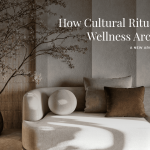 A peaceful, minimalist interior featuring a curved neutral sofa layered with textured pillows, a rustic ceramic vase holding a delicate flowering branch, and a softly lit textured wall. The natural materials, warm tones, and quiet composition reflect wellness design shaped by cultural rituals, evoking spaces where tradition and contemporary architecture meet to support calm and restoration.