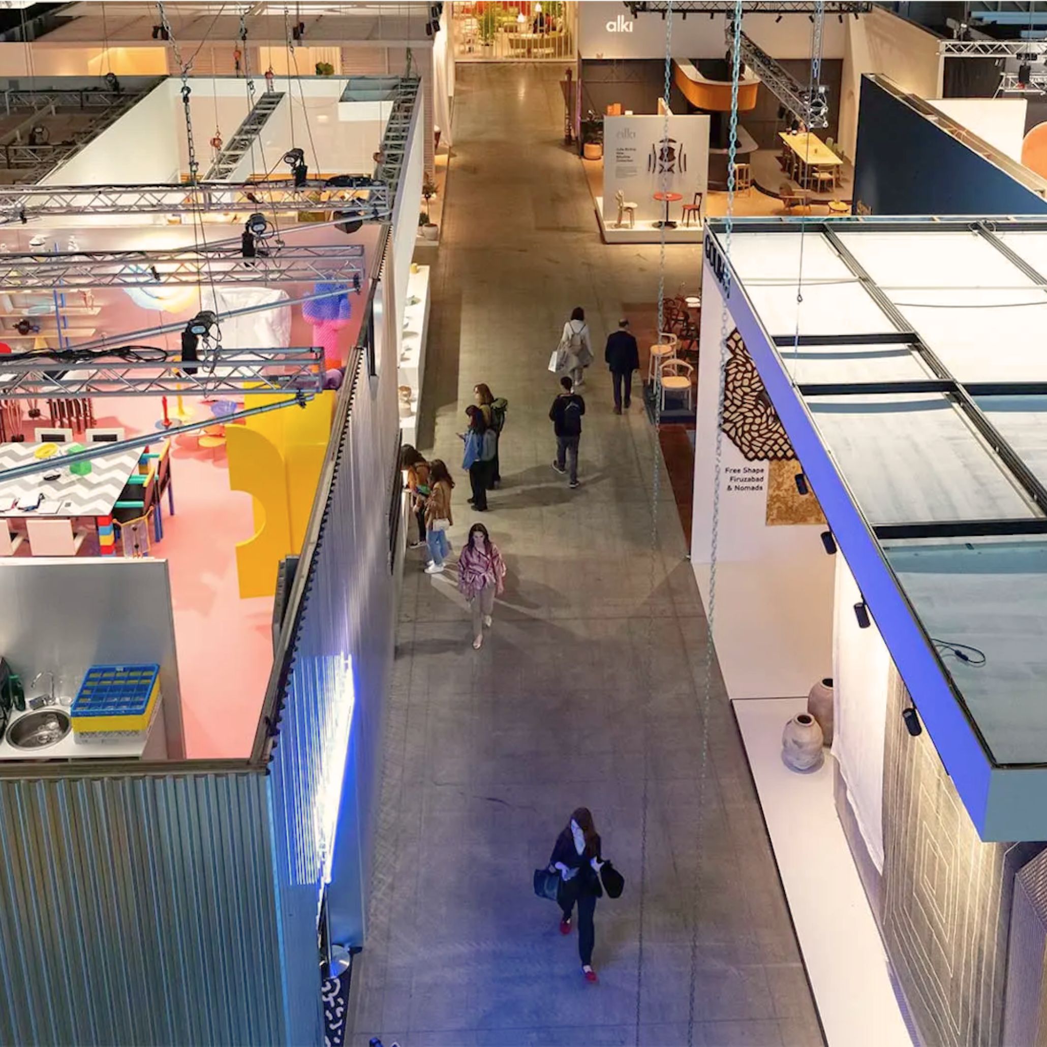 An overhead view of a bustling exhibition hall reveals visitors moving between curated booths that showcase emerging aesthetics, tactile materials, and evolving design philosophies. The diversity of installations reflects how Milan Design Week 2026 continues to influence global interiors, shaping expectations around modern furniture, guiding new forms of interior design inspiration, and redefining the meaning of luxury furniture through craftsmanship and adaptability.