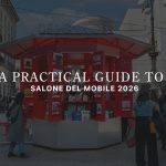 People gather around a bright red Design Kiosk on a busy Milan street, where conversations unfold as visitors browse books and design materials. The scene captures an informal client‑style interaction in the city’s design atmosphere, shaped by interior design inspiration, surrounded by hints of modern furniture culture, and connected to the broader world of contemporary furniture showcased during Salone del Mobile.