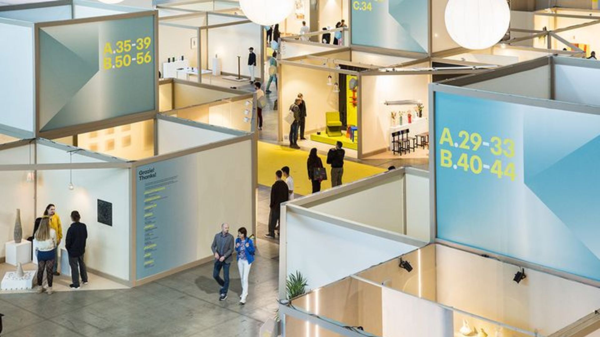 An overview of the exhibition halls at Fiera Milano Rho shows visitors navigating the structured layout of Salone del Mobile 2026, moving between stands and design showcases. The organised grid of booths reflects the scale and rhythm of the fair, helping professionals orient themselves while exploring interior design, discovering new modern furniture, and engaging with the latest directions in luxury furniture.