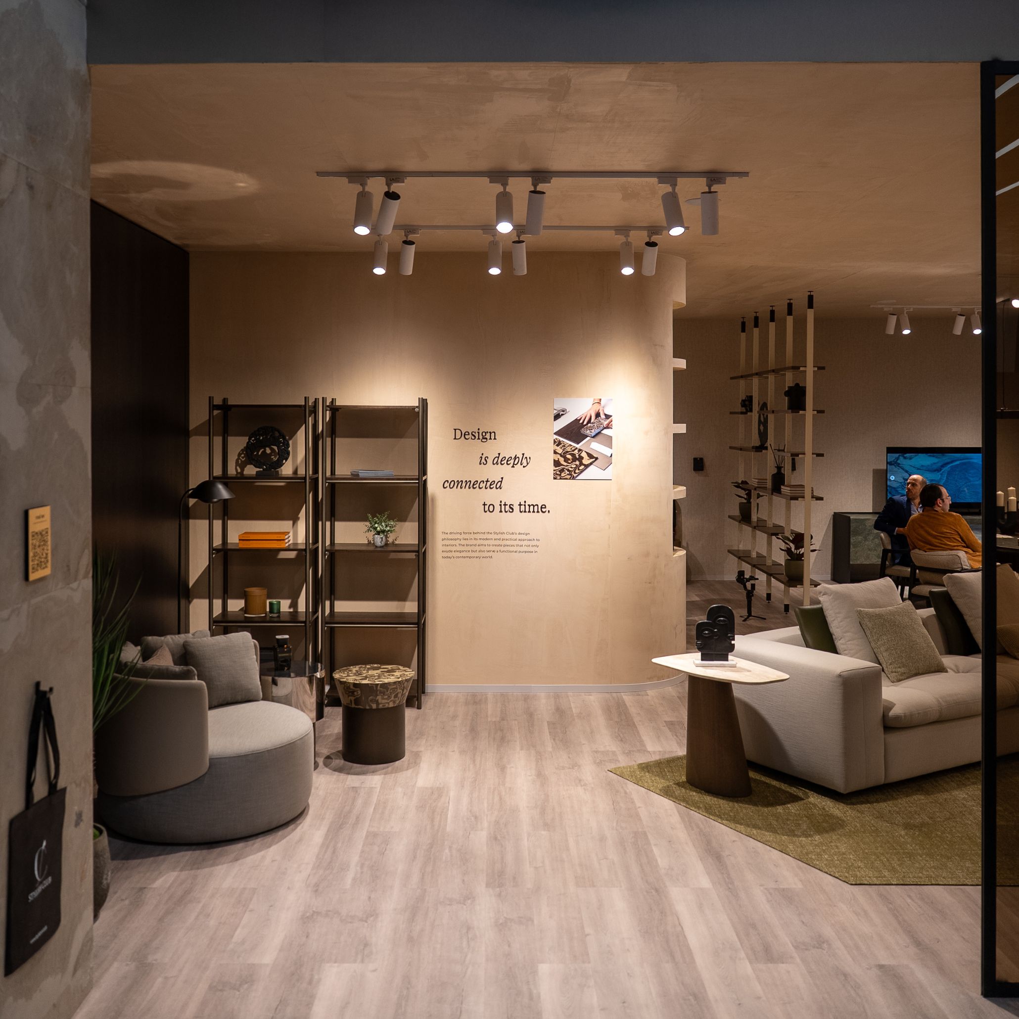 A contemporary showroom displays modern furniture, shelving, and a design‑focused quote, representing the variety of spaces visitors encounter at Salone del Mobile 2026. The setting highlights how exploring different pavilions reveals evolving furniture design, showcases emerging design trends, and supports intentional movement through the fair’s exhibition spaces connected to interior design inspiration and the world of modern furniture.