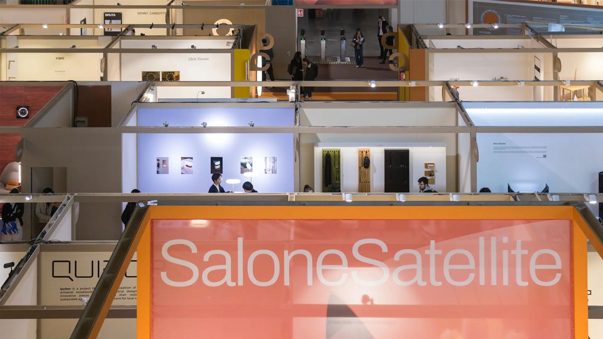 Visitors explore the SaloneSatellite area at Salone del Mobile 2026, where emerging designers present experimental work across dedicated booths. The space highlights early creative directions that influence the wider fair, offering insight into emerging designers, showcasing innovative furniture design, and revealing forward‑thinking design trends connected to interior design inspiration and contemporary furniture.