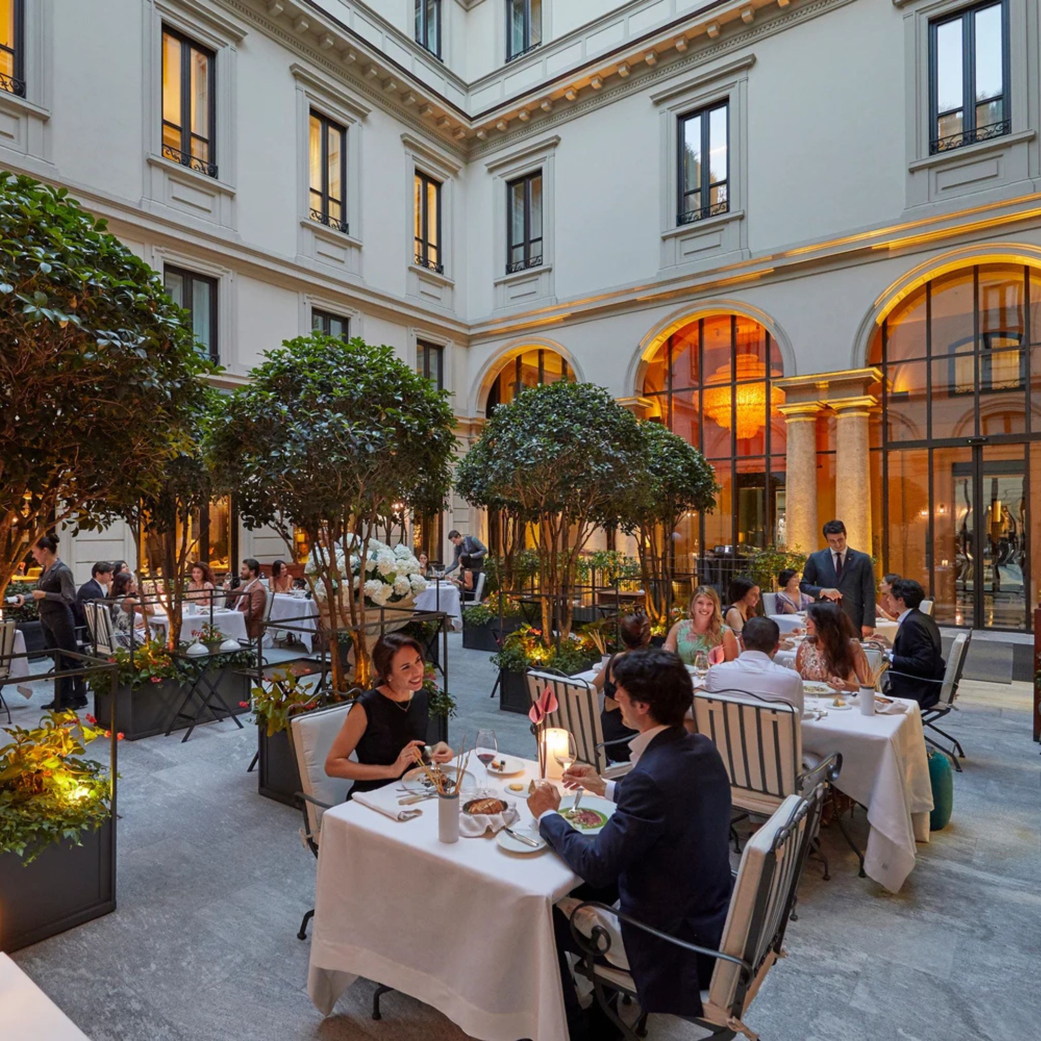 An elegant courtyard at Seta Restaurant hosts diners in a refined, softly lit setting, offering a moment of pause during Milan Design Week. The atmosphere blends architectural charm with the city’s gastronomic culture, echoing the crafted detail found in restaurant furniture, the sophistication of hospitality designs, and the lifestyle sensibility that shapes luxury dining room furniture, enriched by restaurant decor ideas and modern restaurant dining chairs.