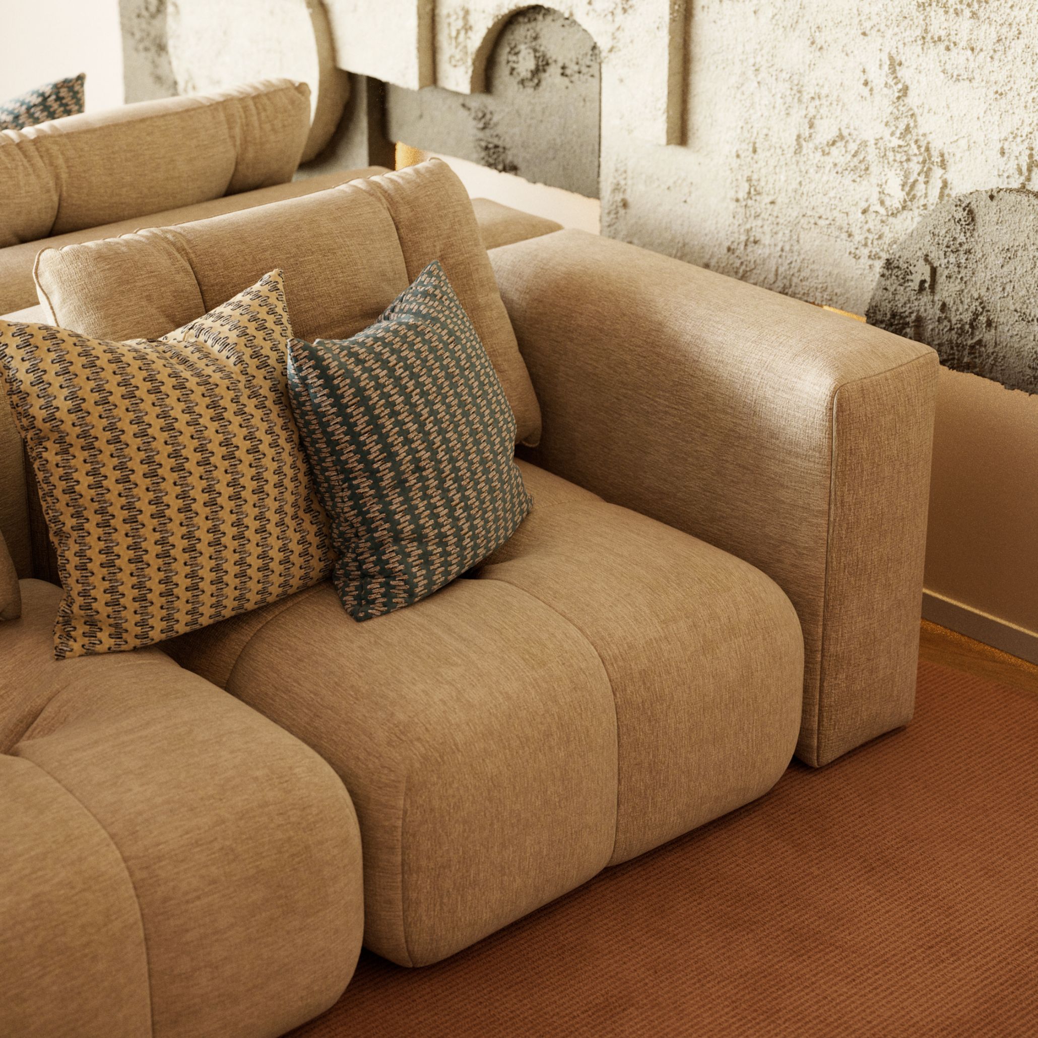A close-up of the Antónia Sofa in textured beige fabric, paired with geometric patterned pillows in yellow, blue, and neutral tones. The soft, rounded cushions and subtle fabric weave emphasize comfort and material depth, echoing the essence of contemporary furniture, the crafted detail of luxury home furniture, and the tactile presence that defines living room furniture. The abstract wall behind it reinforces the elemental focus on texture, form, and quiet balance.