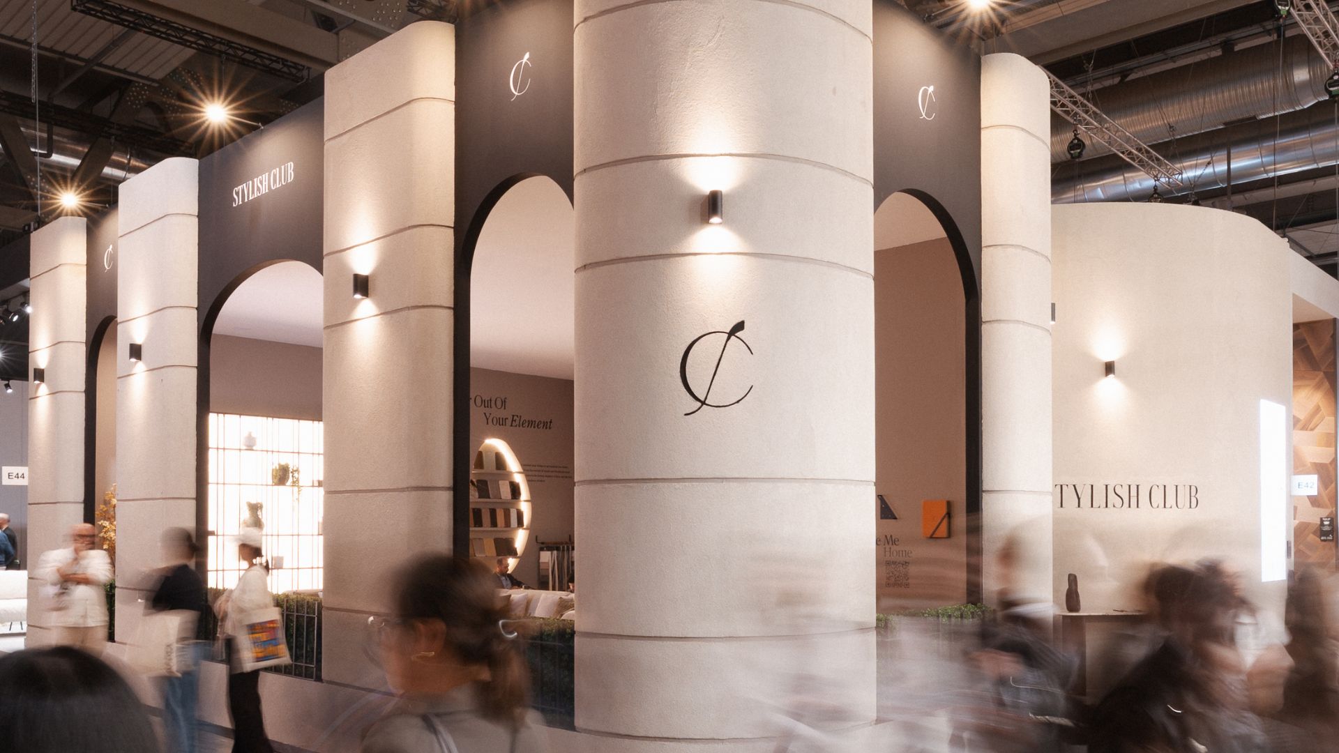 The exterior of the Stylish Club stand at Salone del Mobile 2026 reveals soft architectural curves and warm lighting that frame the entrance with a calm, elemental presence. Visitors move past the sculptural façade, drawn to its natural tones and refined atmosphere, where the brand’s vision for luxury home furniture begins to unfold. The stand’s crafted structure highlights the precision of bespoke furniture, while its serene composition offers a quiet moment of interior design inspiration within the flow of the fair.