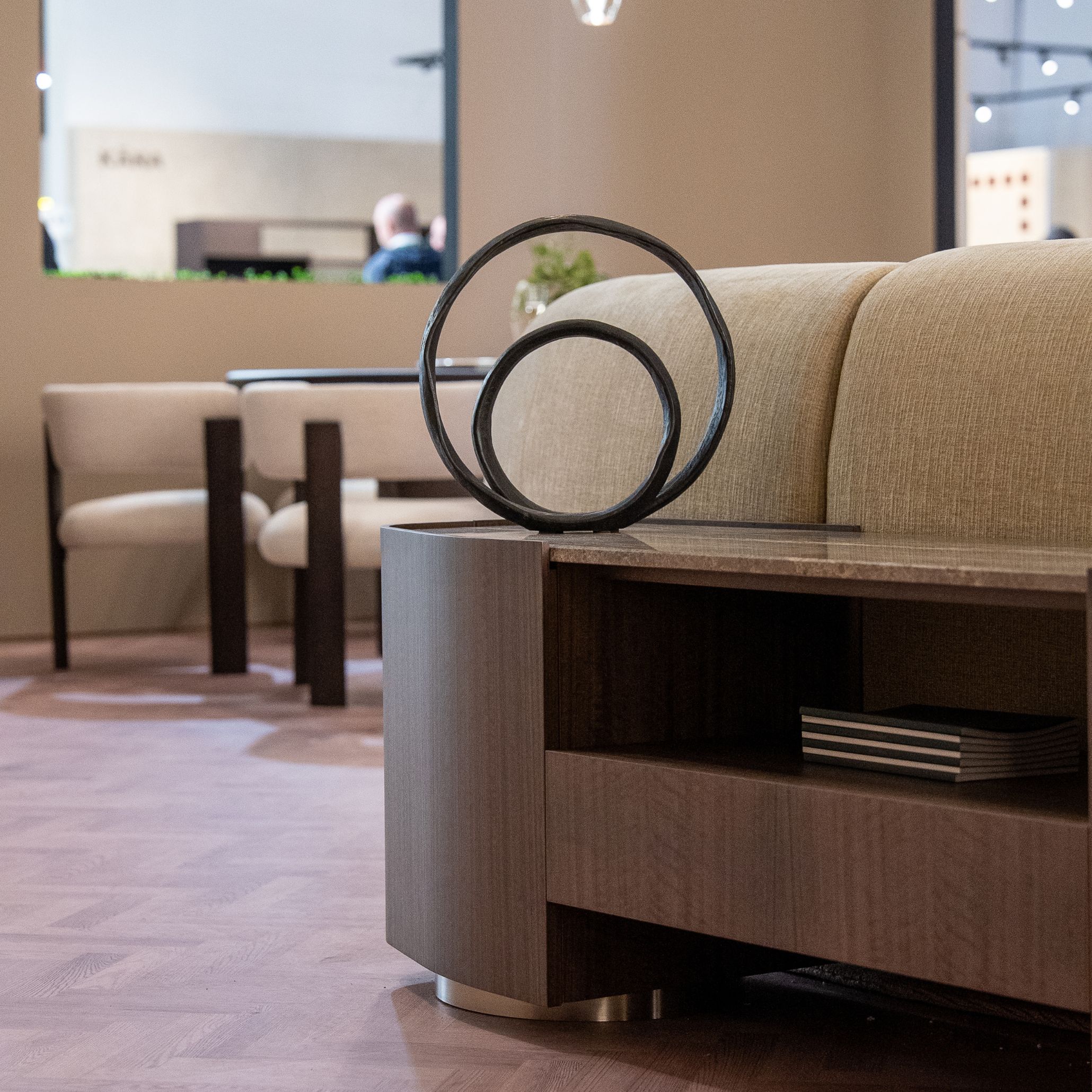 The Stone Low Console defines the transition between spaces with its clean lines, warm wood tones, and refined marble accents. Styled with sculptural decor and soft ambient lighting, it reinforces the architectural rhythm of the stand while connecting the living and dining settings. This piece embodies the clarity of modern furniture, the crafted precision of casegoods furniture, and the understated sophistication found in thoughtful design details.