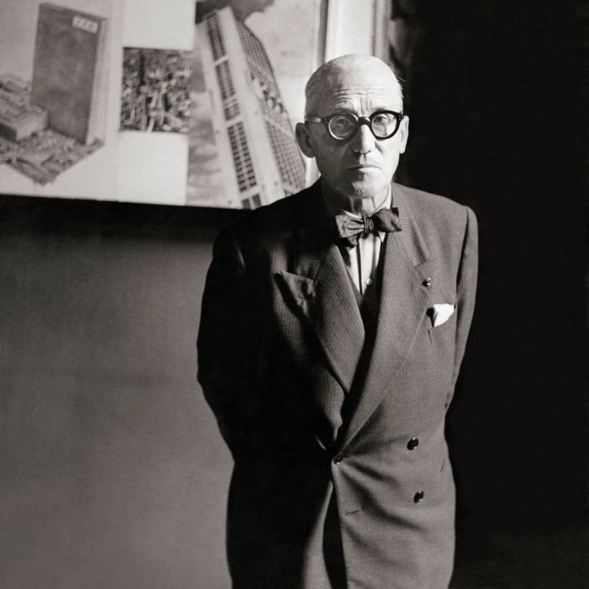 A portrait of Le Corbusier standing before his architectural drawings, embodying the disciplined vision that shaped modern architecture and informed his approach to luxury furniture, bespoke furniture, and the functional ideals that continue to guide contemporary furniture design.