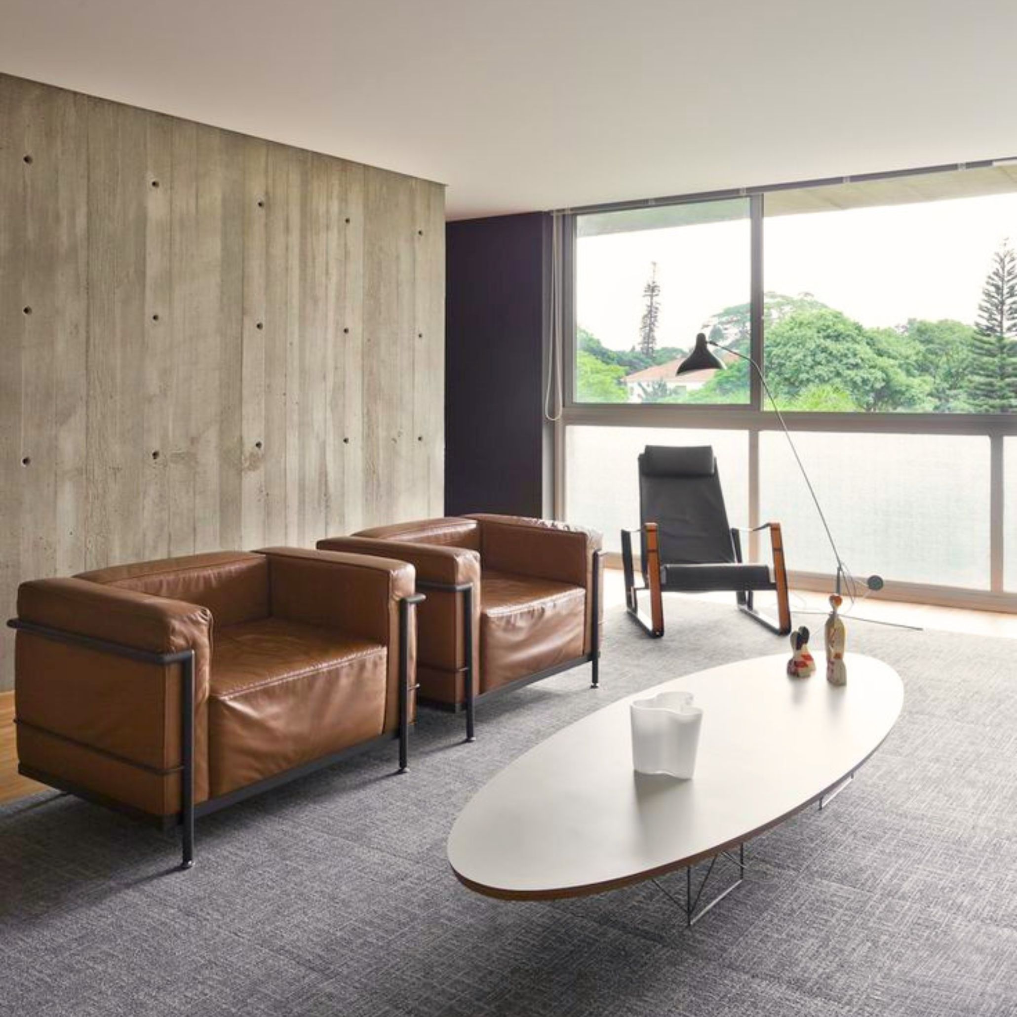 A minimalist living room with structured seating that echoes the clarity of the Le Corbusier LC2 Chair, where exposed frames and defined volumes reflect the principles behind modern luxury furniture, the precision of high end furniture, and the architectural balance often seen in luxury living room furniture.
