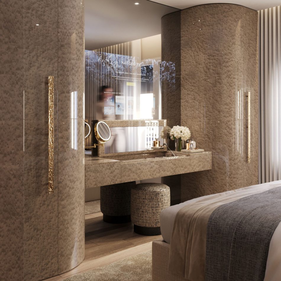 The vanity area features a marble countertop with gold accents, styled with flowers, perfumes, and a magnifying mirror. The Sublime Stool sits neatly beneath the dressing table, adding softness to the reflective surfaces and warm lighting. This intimate corner expresses luxury master bedroom furniture, supported by crafted modern furniture, and elevated through thoughtful design details.