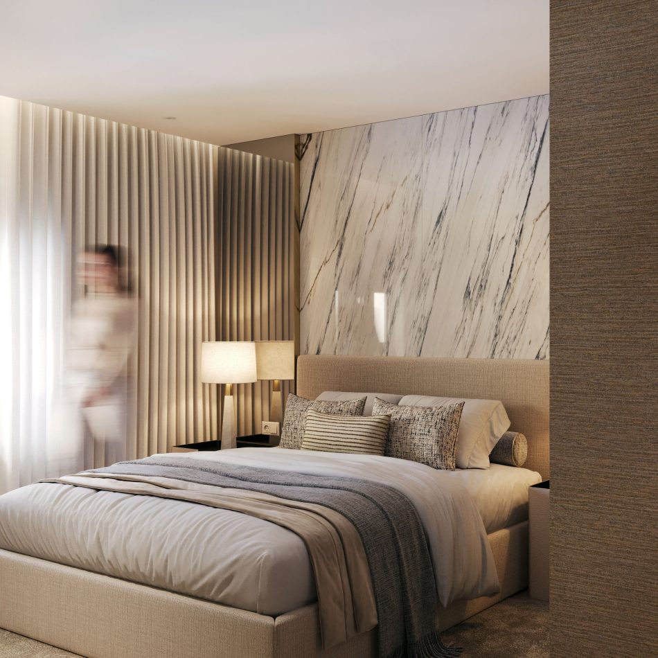 The bedroom features a soft upholstered bed dressed in layered neutrals, set against a marble‑veined feature wall that adds quiet drama. Warm lighting and textured panels create a serene atmosphere, with a blurred figure adding a sense of lived‑in movement. This setting embodies luxury master bedroom furniture, complemented by elegant modern furniture, and arranged to inspire calming bedroom design ideas.