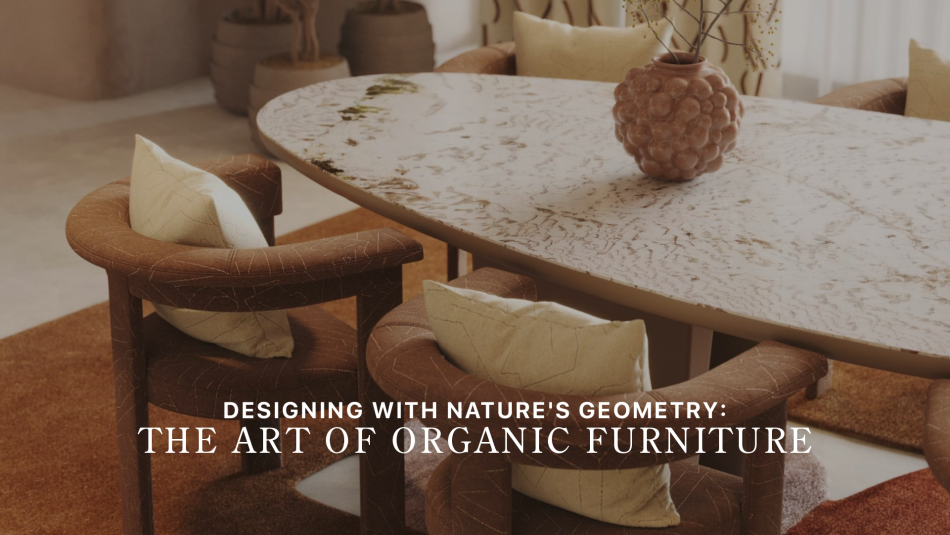 The Stone dining table with soft mineral veining sits surrounded by curved upholstered chairs, illuminated by warm natural light and framed by earthy textures. A sculptural vase with delicate branches anchors the composition, introducing the calm, grounded aesthetic of nature‑led design. The scene reflects expressive organic furniture, the warm tactility of natural interiors, and the sculptural clarity of contemporary design.