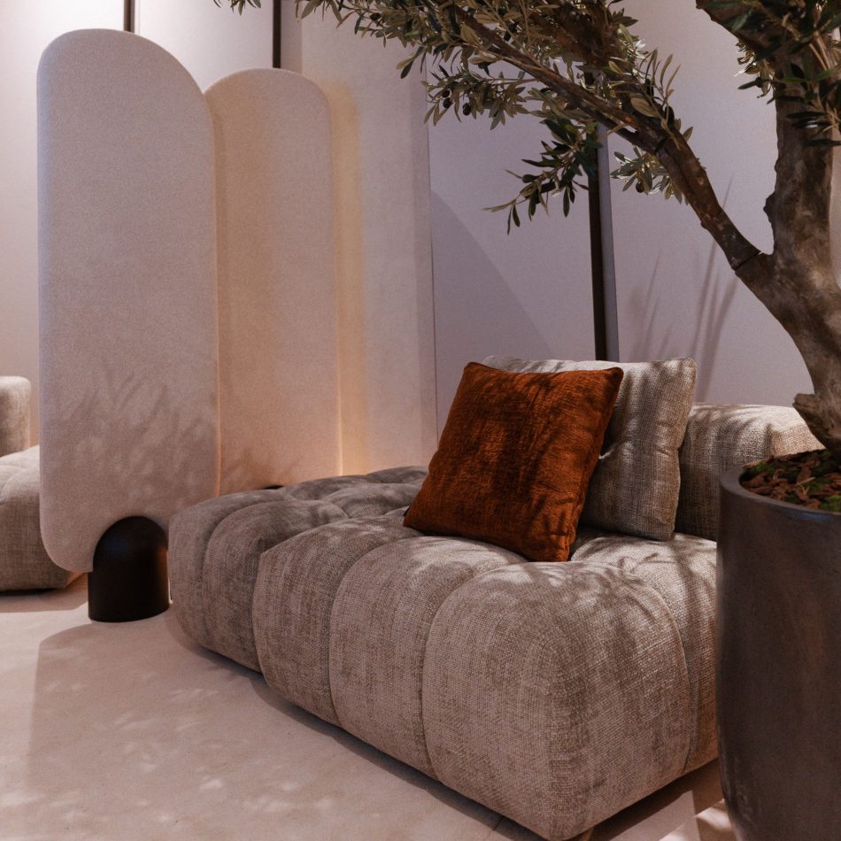 A serene private area showcases the Antónia Modular Sofa paired with a rust‑toned cushion, set beside a softly curved Stone Screen that defines the space. Warm lighting, natural textures, and sculptural forms contribute to an intimate corner shaped by high end furniture and expressive interior design inspiration.