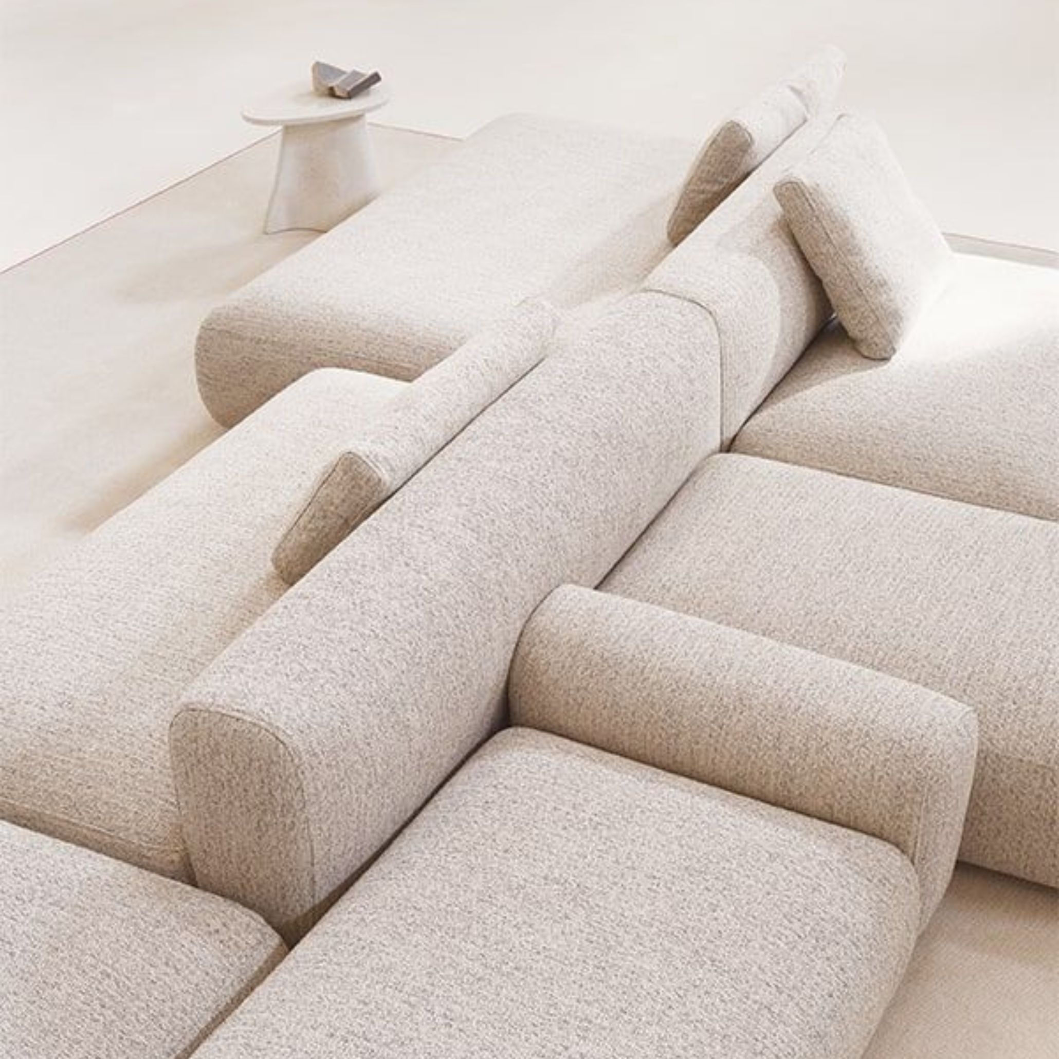 Light‑toned modular sofas are arranged in a clean, linear composition, with soft cushions and geometric forms creating a calm, minimalist atmosphere. The overhead view highlights how individual modules can be combined or separated, reflecting the adaptability central to modern sofa design. Neutral tones, rounded side tables and subtle styling reinforce the flexibility and elegance associated with contemporary furniture.