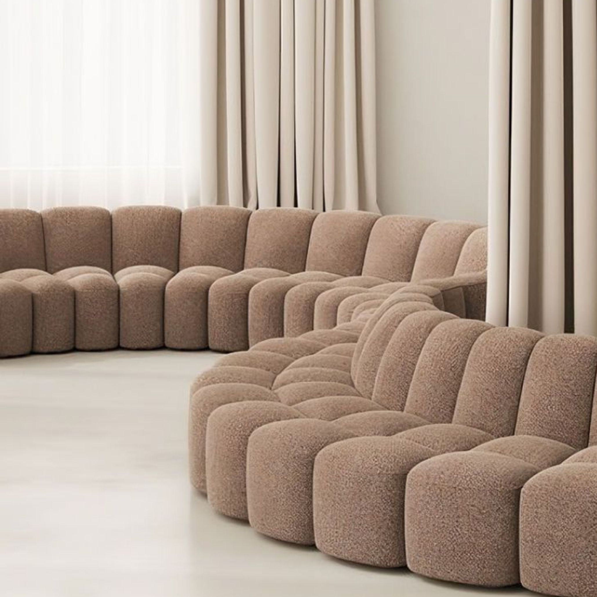 A curved arrangement of bouclé modular sofas forms an inviting seating area, showcasing how interconnected modules can create fluid, organic layouts. The soft beige upholstery, rounded silhouettes and warm natural light emphasize the freedom to reconfigure pieces as spaces and routines evolve, embodying the versatility of modern sofa design within serene contemporary furniture interiors.