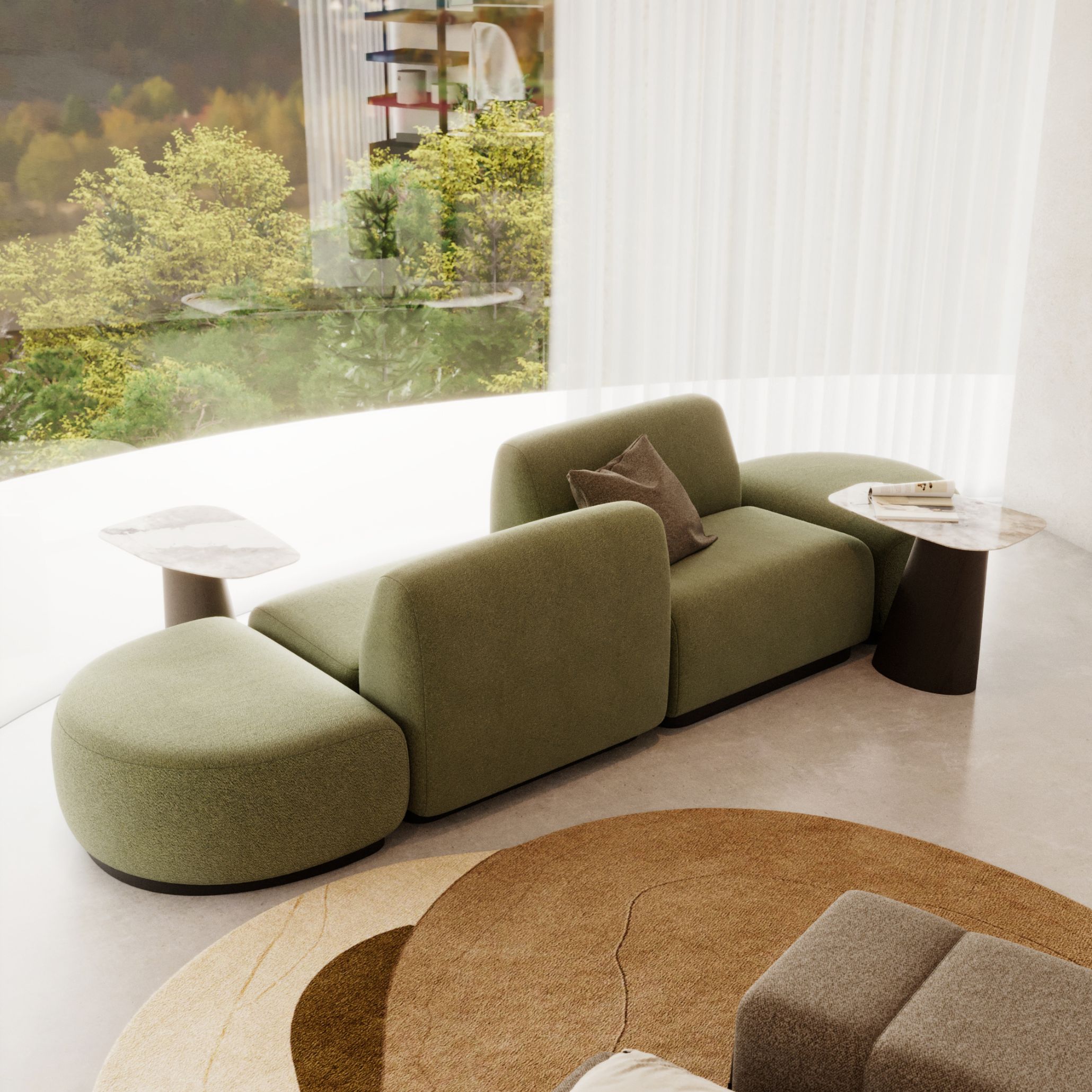 A sculptural arrangement of the Stone Sofa sits in front of floor‑to‑ceiling windows, its rounded green modules expressing the adaptability of modern modular sofas. Paired with marble‑topped side tables and a layered circular rug, the composition highlights a fluid sofa design capable of evolving with changing routines. The bright, nature‑filled backdrop reinforces the connection between contemporary furniture and flexible living spaces.