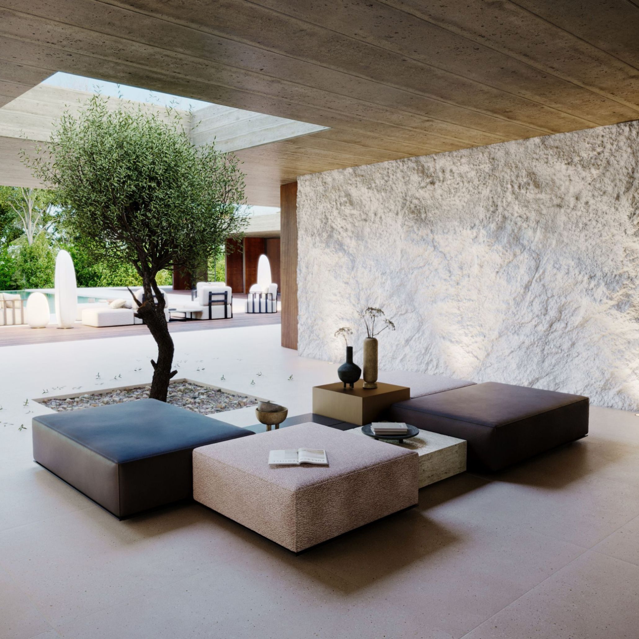 The Landform Modular Sofa is arranged in a low, sculptural outdoor composition, with square modules in soft neutral tones placed around a central stone‑filled opening where a tree grows beneath a skylight. The layout highlights the expressive potential of modular sofas, creating an organic seating landscape that blends seamlessly with the surrounding architecture. Decorative objects rest on the modules, while textured stone walls and views of greenery reinforce a serene, minimalist approach to sofa design within contemporary furniture environments.