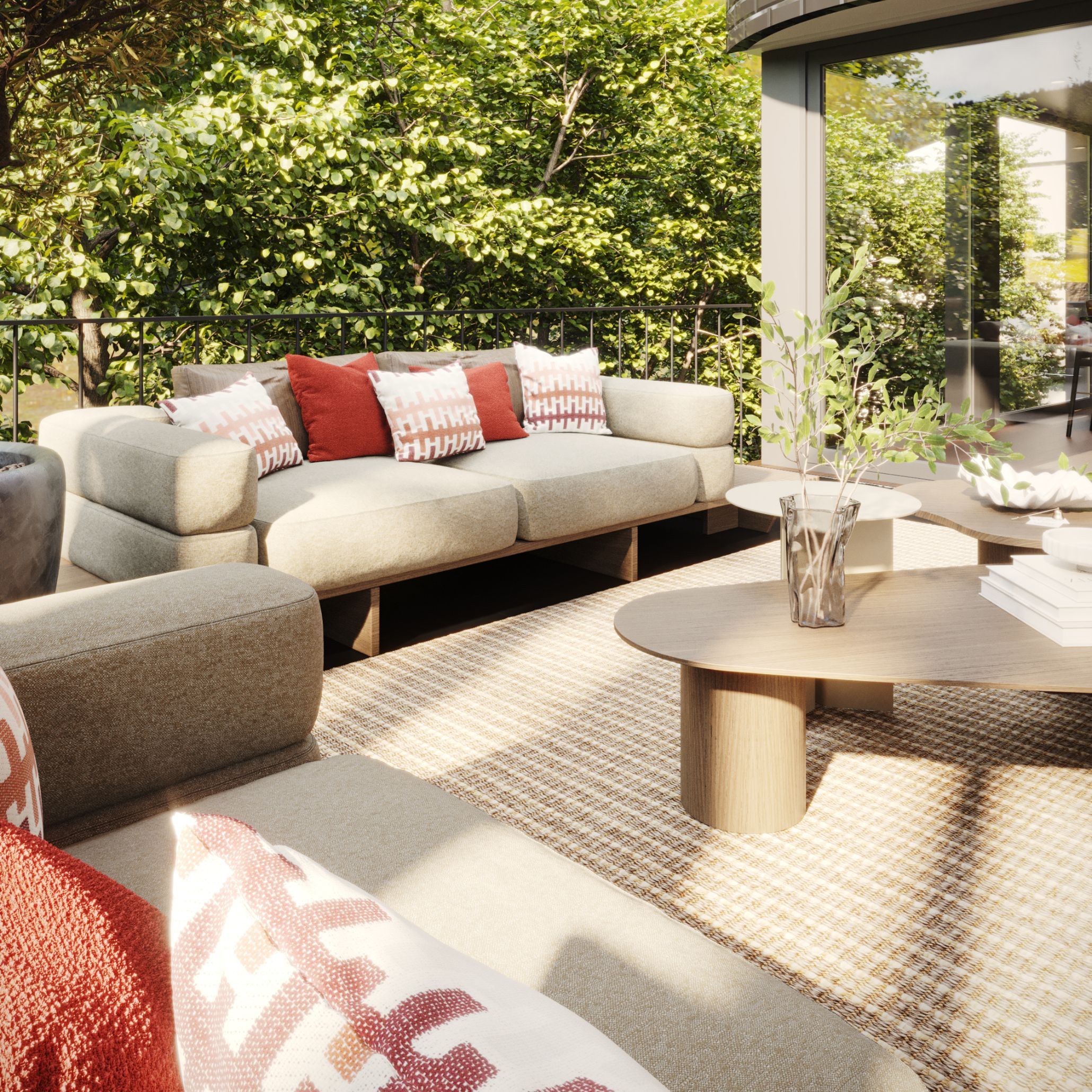 The Ripa Sofa in warm grey furniture upholstery fabric with terracotta and patterned cushions sits on a woven outdoor rug alongside the Natur Coffee Table in natural solid wood with a cylindrical pedestal base. This bespoke living room terrace setting, framed by lush green trees and floor-to-ceiling glass, captures the Comporta principle that living room furniture moves effortlessly between interior and outdoor living spaces.