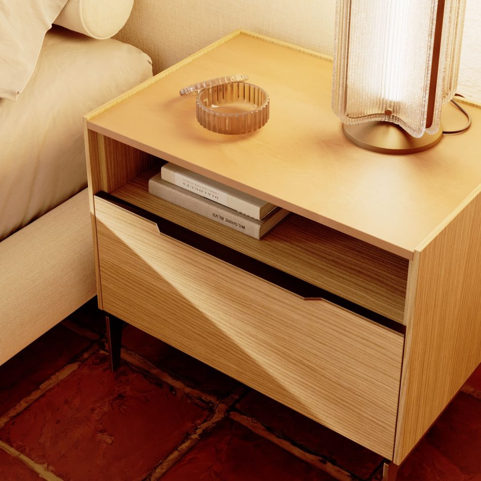 Close-up of the Landform Night Table I beside a linen upholstered bed, showing the natural oak solid wood body bathed in warm afternoon light, with the drawer gently pulled open to reveal its precise craftsmanship. The metal legs and gold-metal leg caps ground the piece with precision - study in design details and best handmade techniques suited to the most considered luxury master bedroom furniture settings.