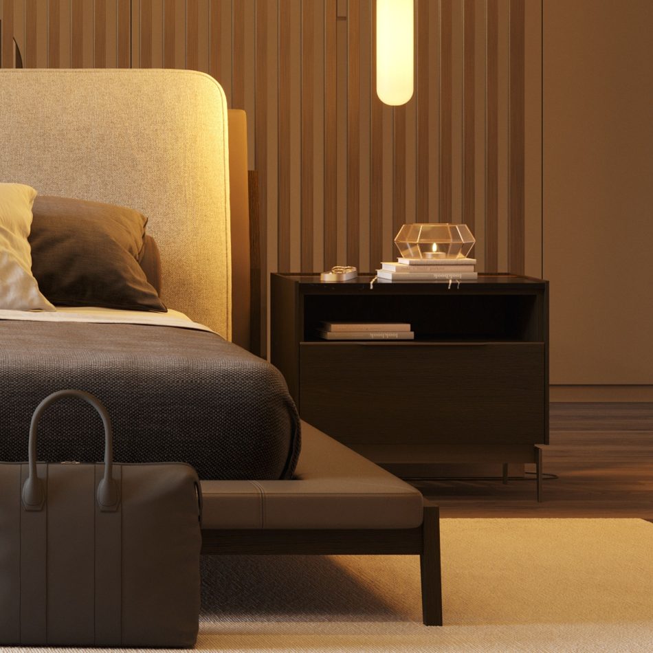 Warm, dimly lit luxury master bedroom furniture setting with a vertical wood slat feature wall, upholstered bed with ochre and brown cushions, and the Landform Night Table I in dark wood texture alongside. The piece holds a candle, stacked books, and a pendant lamp glows above - a quiet moment of interior design inspiration where solid wood and slender metal legs anchor the space with calm precision.