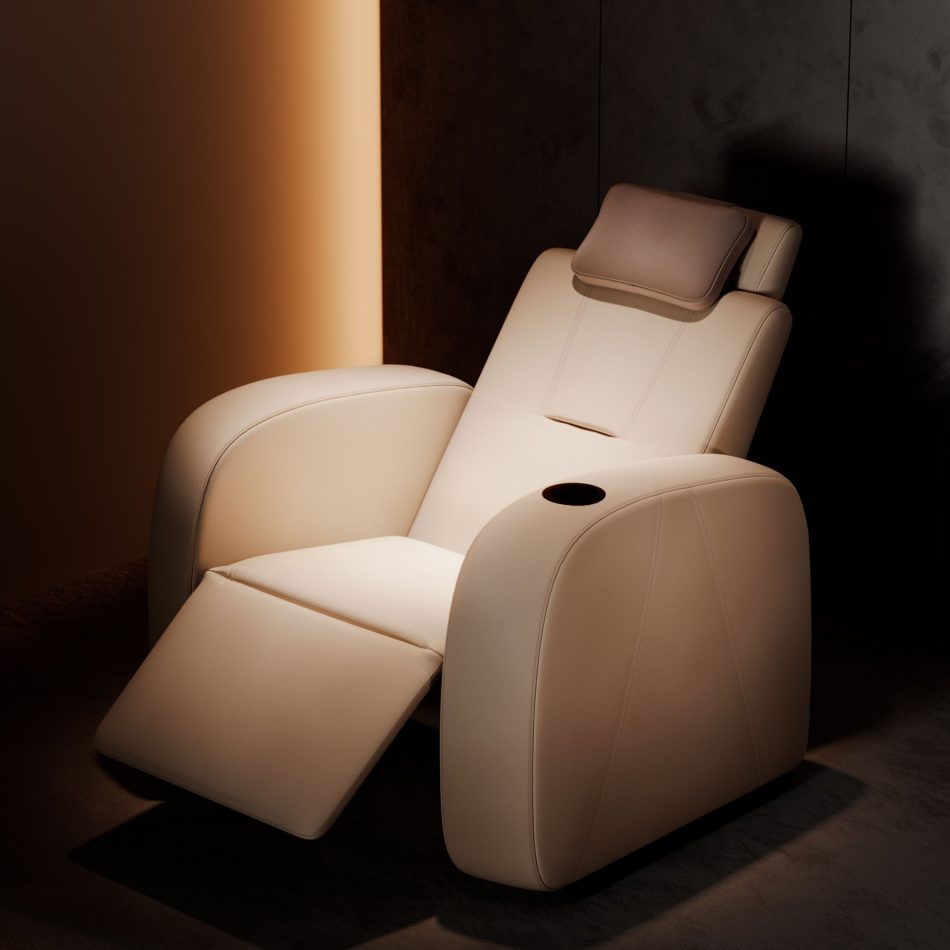 Lumière Cinema Armchair in cream leather upholstery shown fully reclined with footrest extended and adjustable headrest raised, photographed view against a warm amber-lit interior. The integrated black cup holder, clean topstitching, and majestic and sleek silhouette in reclined position reveal the full comfort range of this luxury handmade furniture piece, where minimalist design serves the immersive viewing experience without distraction.