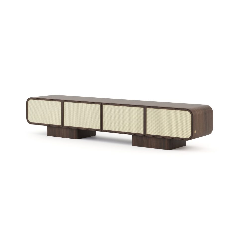 The Natur TV Cabinet is shown in dark walnut at a three-quarter angle on a white background, its rounded silhouette framing four woven rattan front panels in pale contrast. Two block-form bases lift the piece off the ground, reinforcing its sense of lightness despite the deeper tone. This tv cabinet reflects minimalist design through proportion and material honesty.
