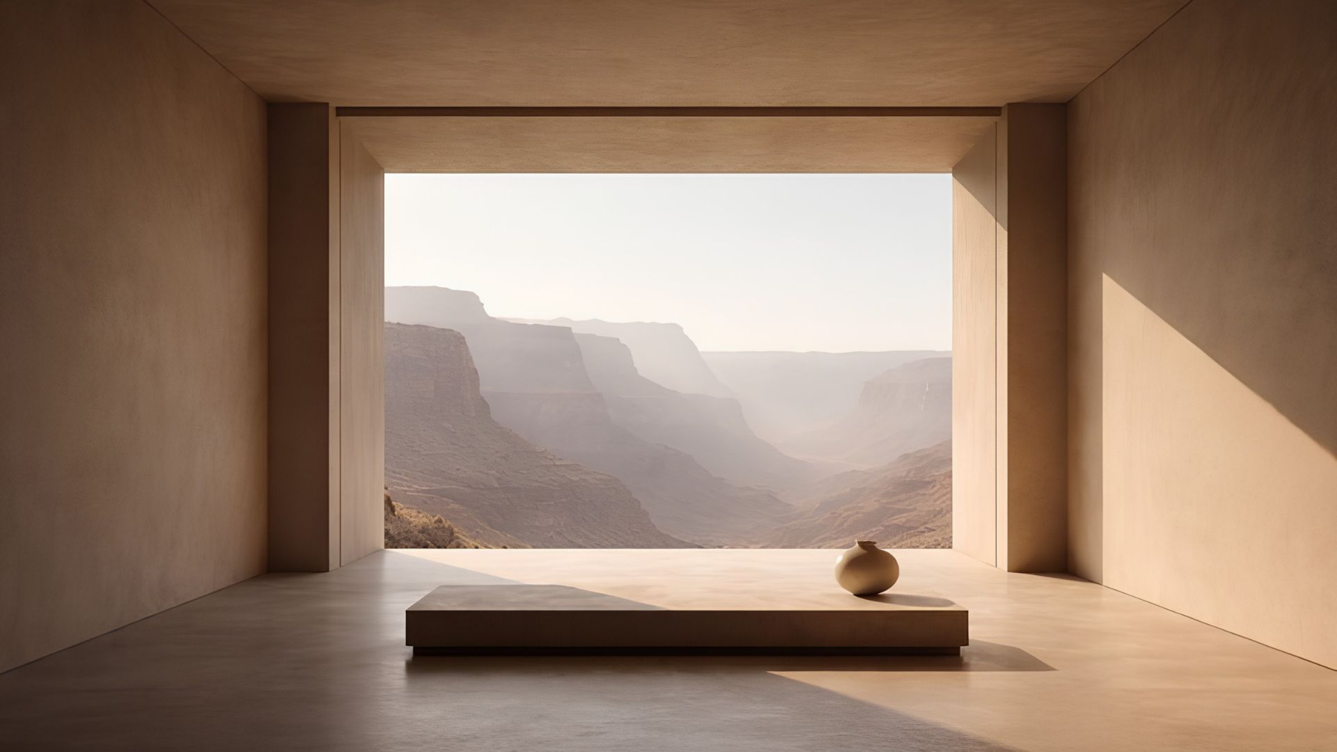 Minimalist earth-toned room with a low stone bench and single ceramic vase framing a vast canyon view, a wellness space where wellness interior design uses light and proportion to support wellbeing.