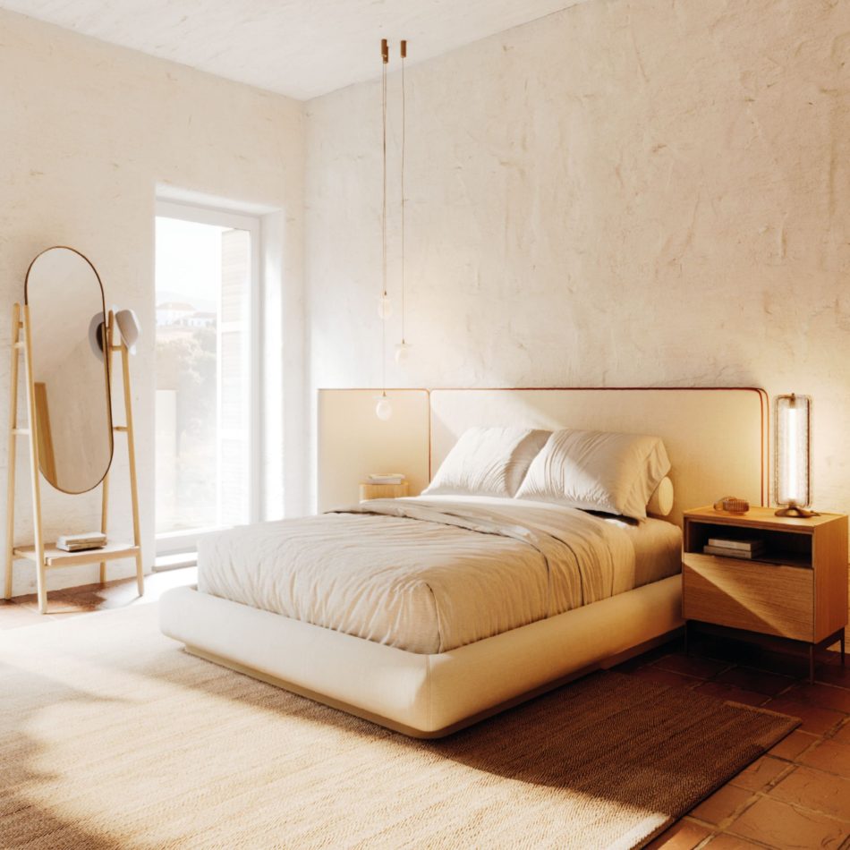 Sunlit master suite with a low upholstered bed, oak nightstand and freestanding oval mirror against a lime-plaster wall, a wellness space where natural light and organic materials support wellbeing.