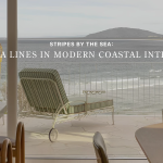 Banner image for "Stripes by the Sea: Riviera Lines in Modern Coastal Interiors" showing a green-and-white striped chaise lounge on a stone terrace overlooking a wide bay, an example of luxury home furniture shaped by Riviera Lines.