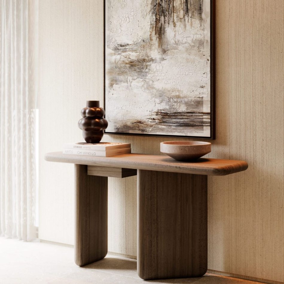 The Foz Console styled in an entrance hall against a textured wall beneath an abstract painting, its wood surface holding a dark ceramic vase, stacked books and a stone bowl. The console's calm, structural presence and warm wood design create a considered display surface, reinforcing the quiet interior design inspiration found in minimalist entryways and living spaces.
