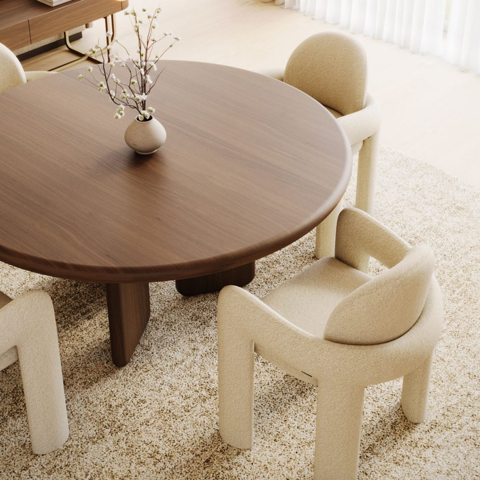 Overhead view centred on the Foz Dining Table's round Alba wood top, holding a small ceramic vase with flowering branches, with two Stone Chairs pulled close at its edge. The grain of the wood reads clearly across the surface, showing the table's material depth and its fit as a luxury dining table within a softly lit dining setting.