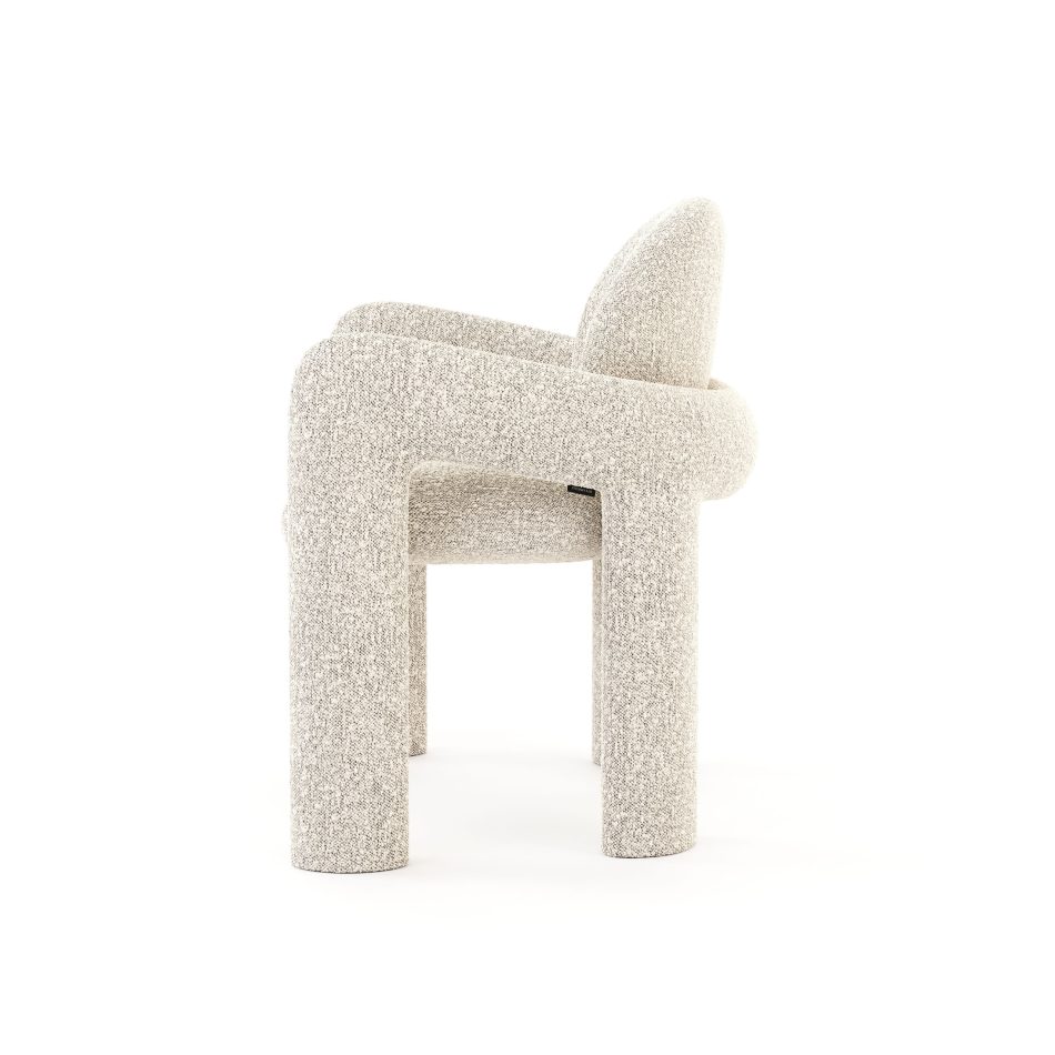 Side profile of the Stone Chair, capturing the continuous line that runs from armrest into backrest and the visible depth and texture of the furniture upholstery along its curved surfaces. The chair's fluid, uninterrupted form offers a clear example of interior design inspiration for modern, pared-back living spaces.