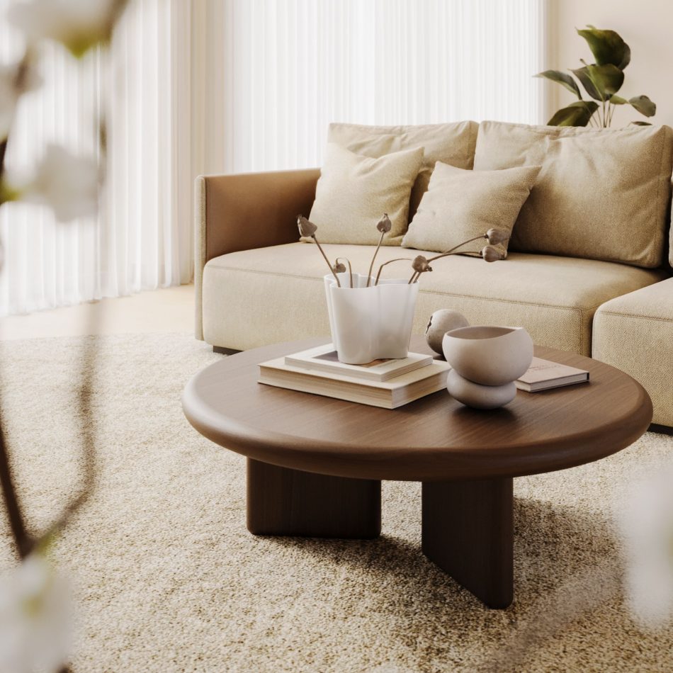 The Foz Coffee Table sits on a light textured rug, its wooden top arranged with ceramic pieces, dried stems, and stacked books. A wooden cabinet and a beige chair complete the warm, minimalist setting, where natural materials shape a calm interior. The vignette reflects thoughtful home furniture in the composition, sculptural design details in the objects, soft living room furniture in the layout, and modern interior design inspiration in the overall feel.