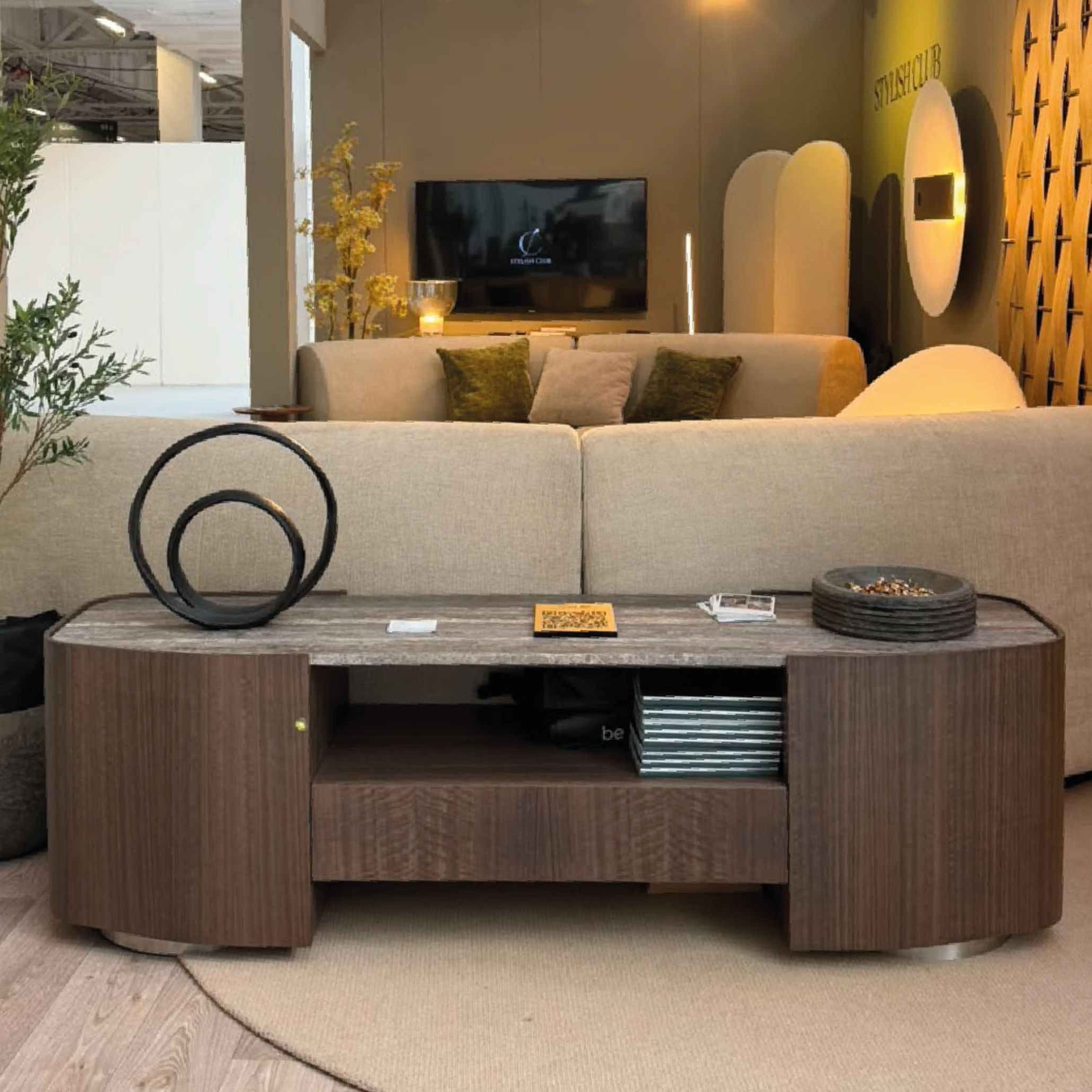 The Stone Low Console placed behind a modular sofa at Stylish Club's Decorex 2026 stand, styled with sculptural decor objects. Combining rich wood grain with a textured stone top, this piece serves as a sophisticated tv cabinet, modern sideboard, and high-end piece of casegoods furniture.