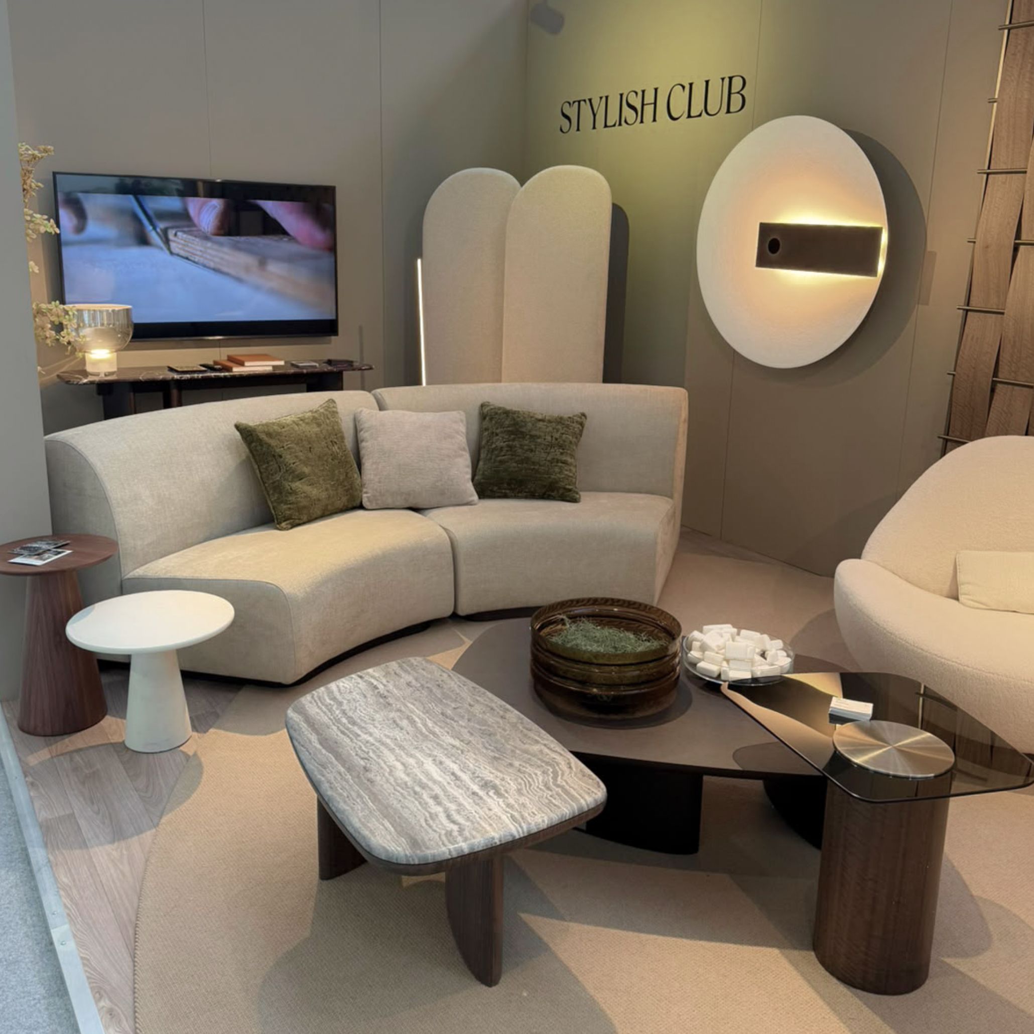 An inviting lounge setting at Stylish Club’s Decorex 2026 stand featuring the Stone Sofa, Dolomites Coffee Table, and the illuminated Meridiana Wall light. The space combines ambient lighting with organic forms to offer complete living room inspiration, elevated design details, and modern luxury living room furniture.