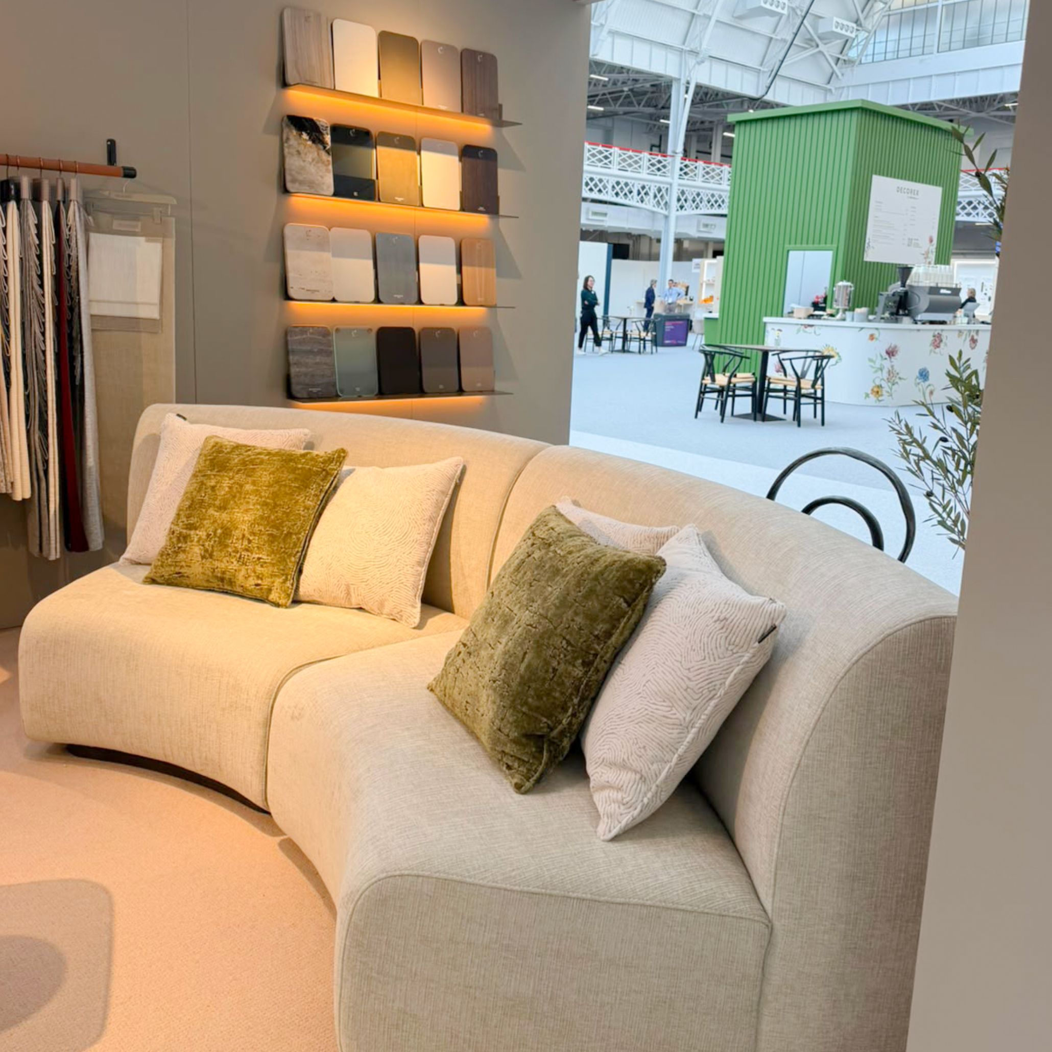A close-up view of Stylish Club's Stone Sofa, highlighting its modular curved volumes and plush textured upholstery accented with olive green throw cushions. Positioned near illuminated material swatches, this piece offers an expressive approach to living room design, custom furniture, and furniture luxury design.